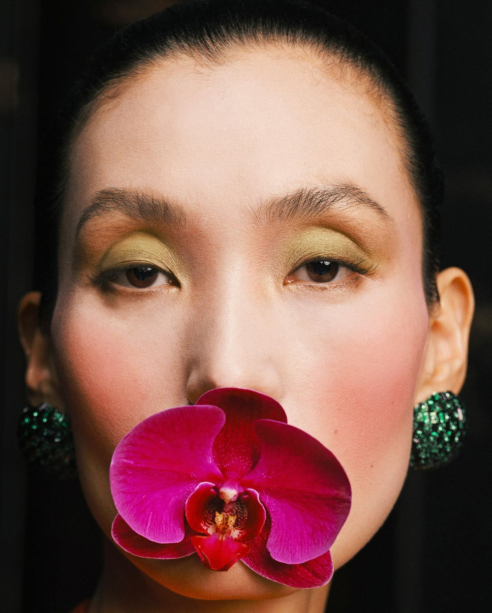 Portrait with an orchid and green earrings